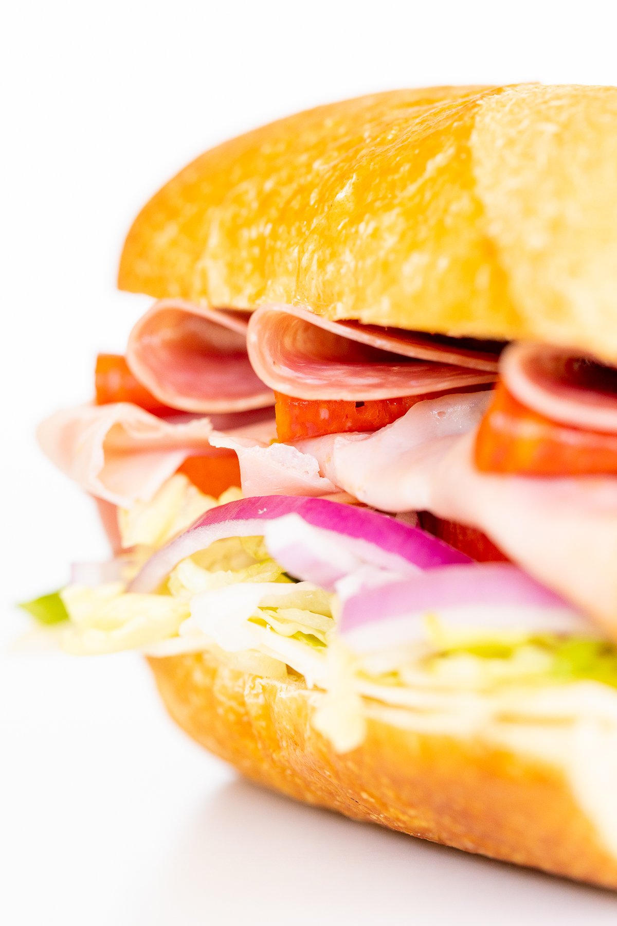 An Italian BMT sandwich with deli meat, lettuce, tomatoes, and onions.