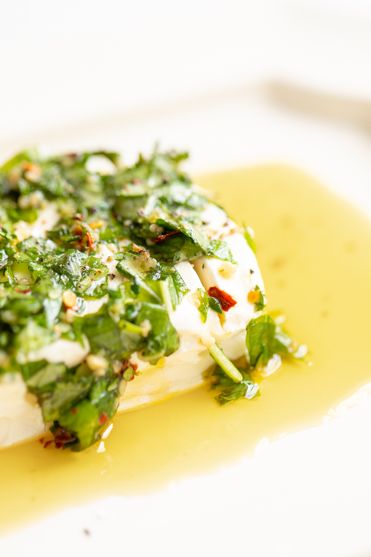 A white plate with a piece of fish in a sauce, perfect for Christmas starters.