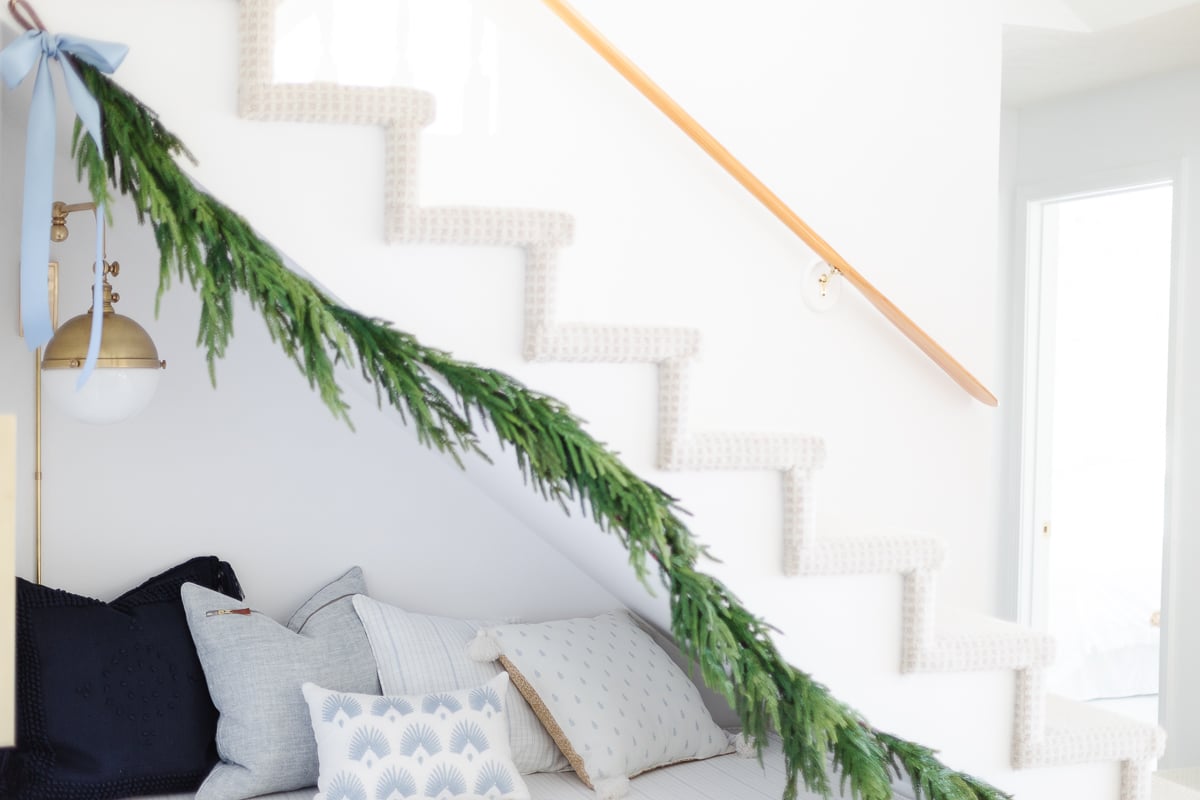 A stairway decorated with garland and pillows.