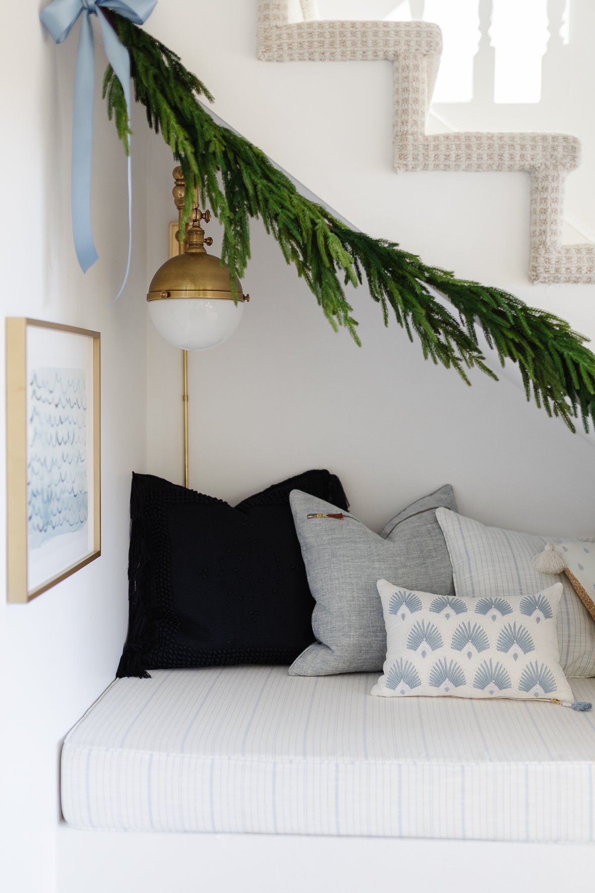 A bed under the stairs with a christmas garland.