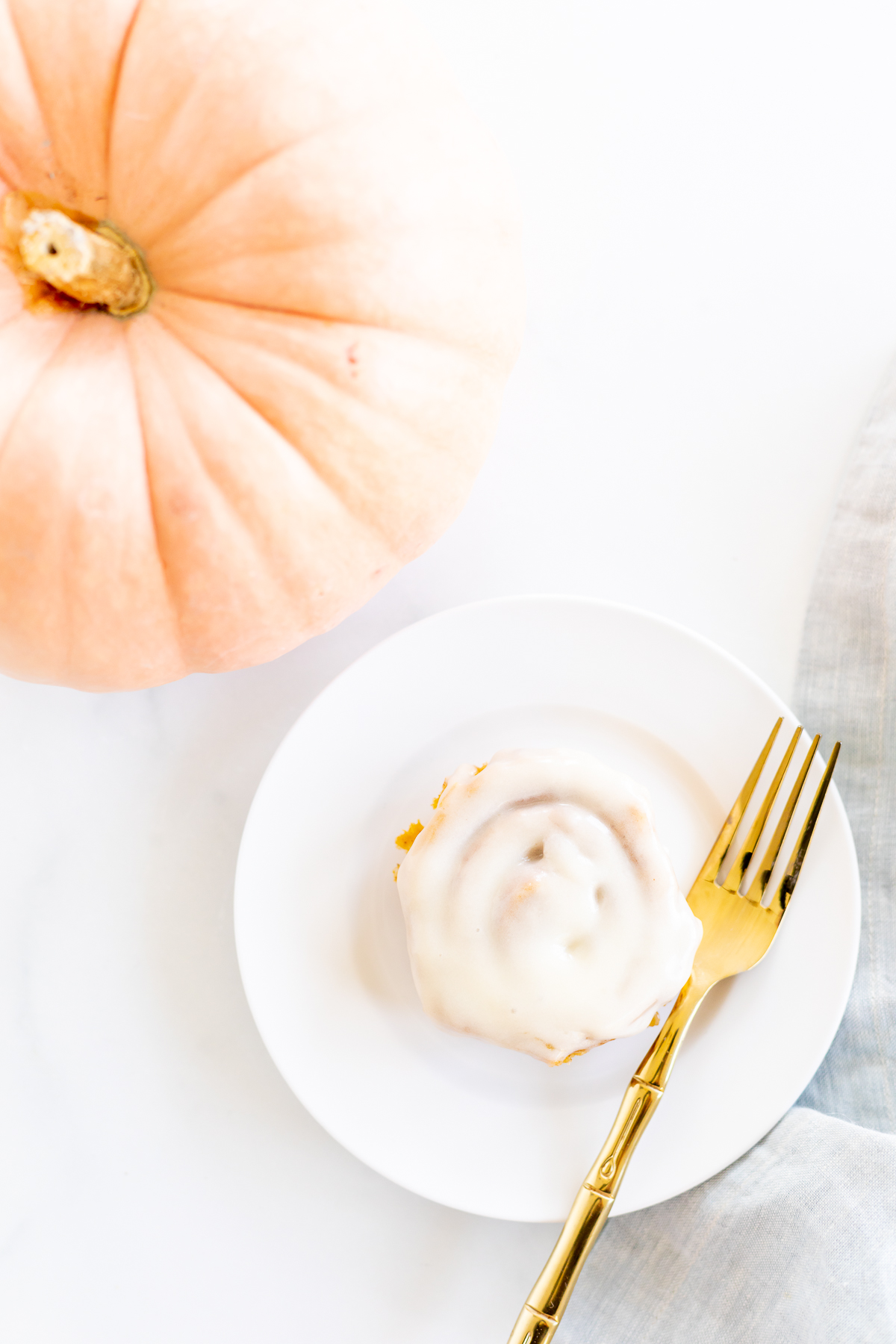 A plate with a pumpkin cinnamon roll and a fork.