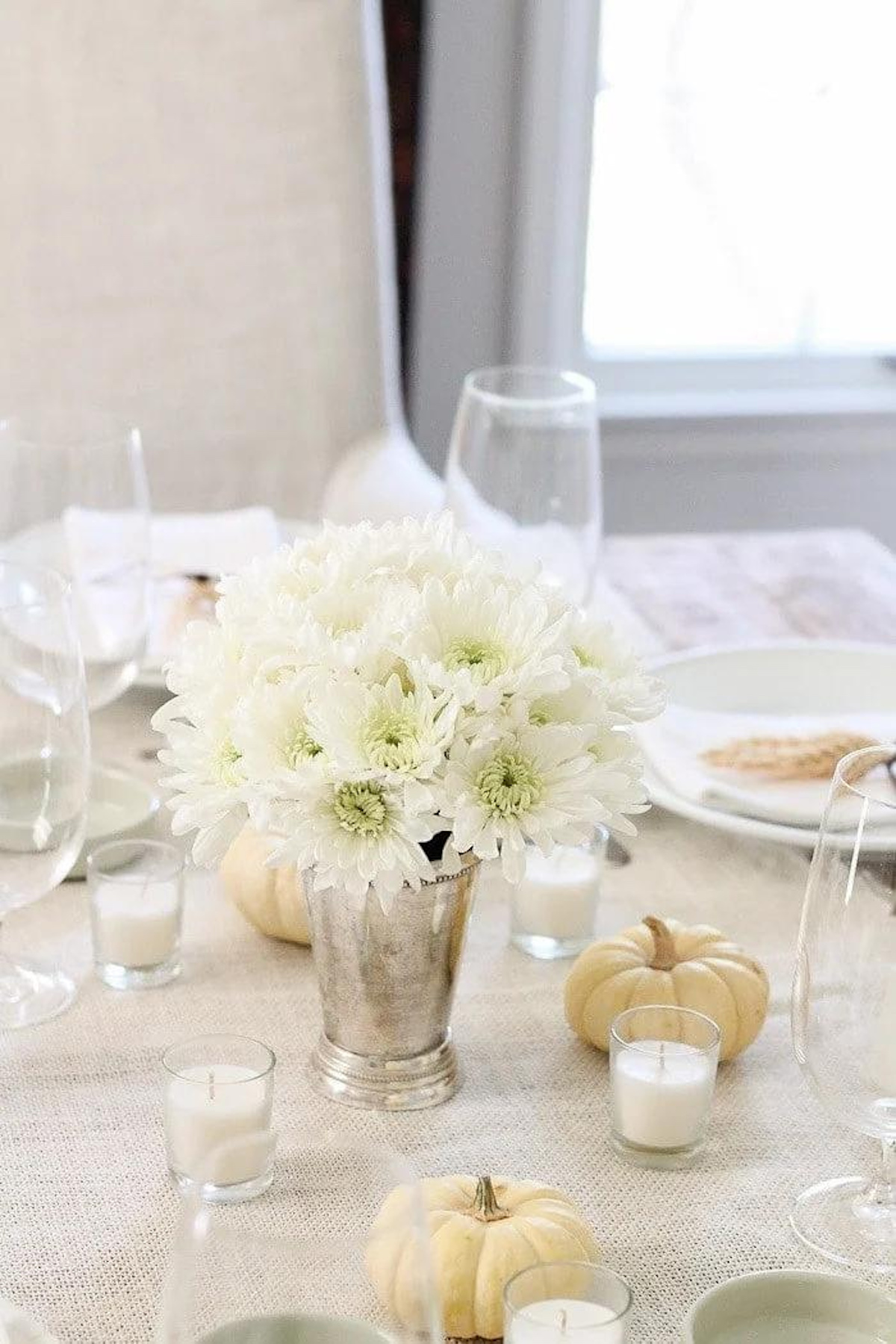 Thanksgiving table setting with white flowers, pumpkins, and Thanksgiving centerpieces.