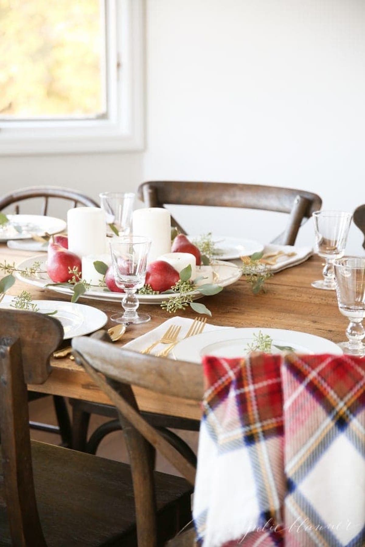 A Christmas table setting with a plaid tablecloth and Thanksgiving centerpieces.