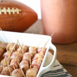 Bacon wrapped pretzels in a dish next to a bottle of beer, the perfect easy chicken appetizer.