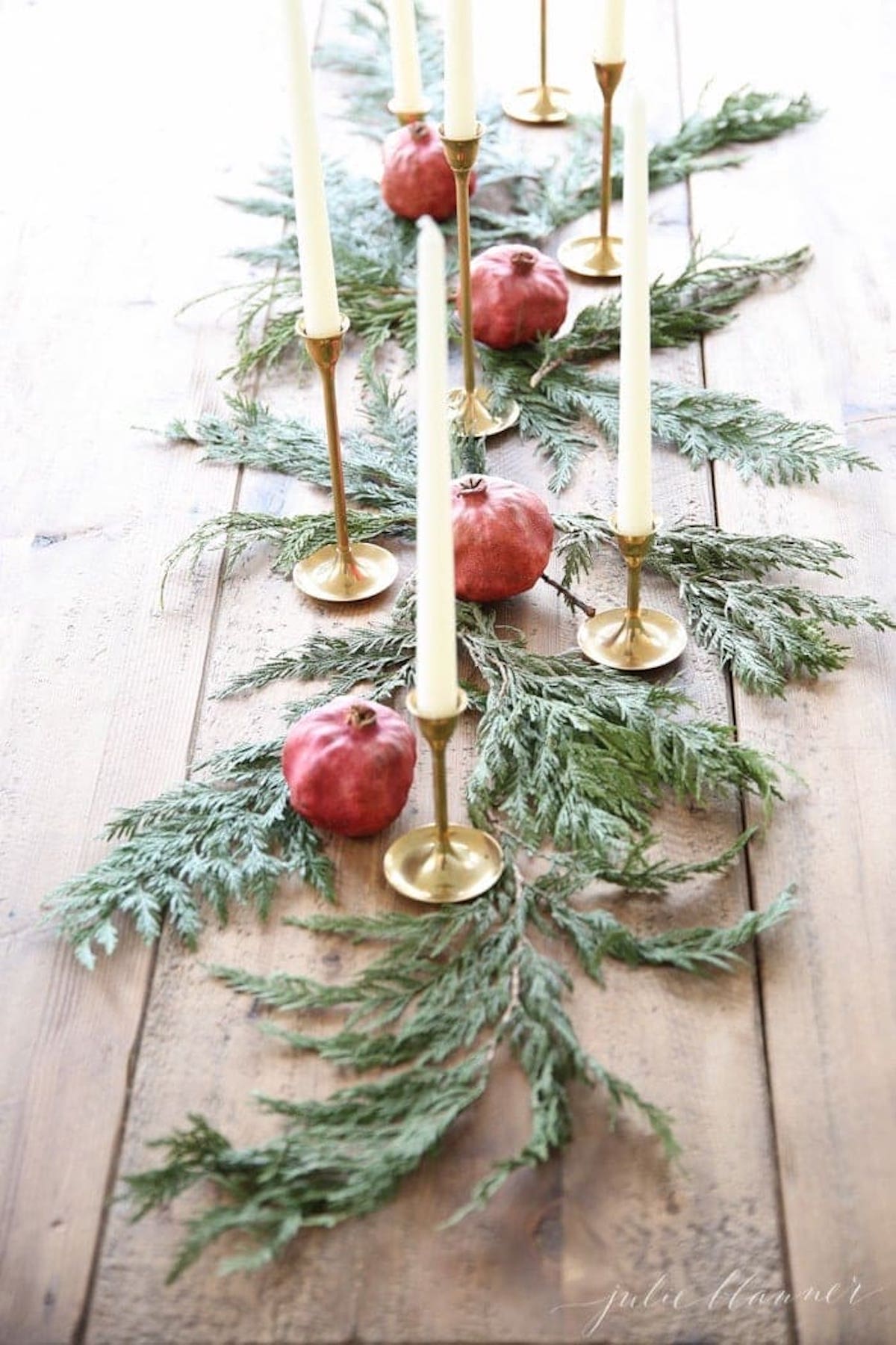 A festive Christmas table runner adorned with pomegranates and greenery, perfect as a holiday candle centerpiece.