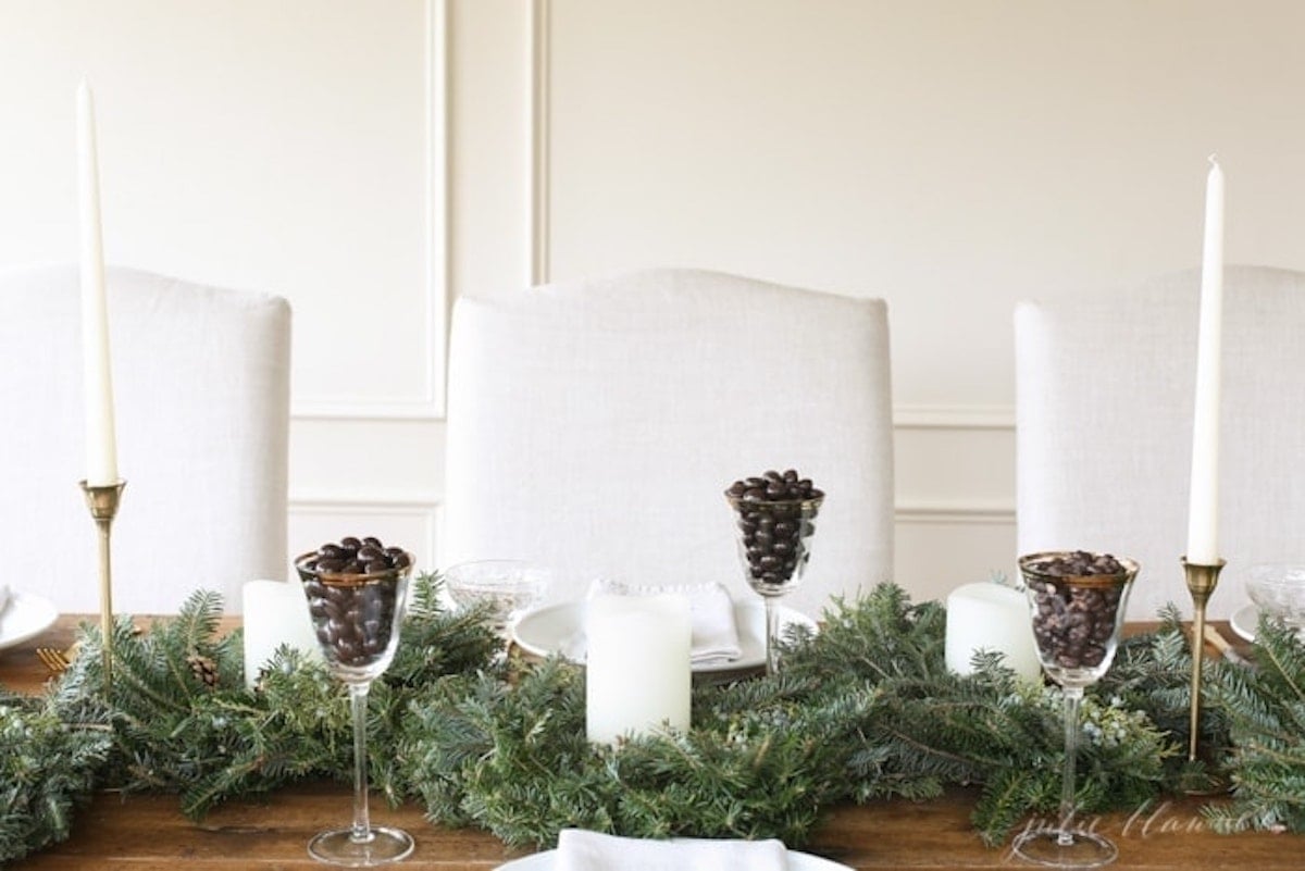 Create a stunning Christmas centerpiece with pine cones and candles, perfect for your holiday table setting.