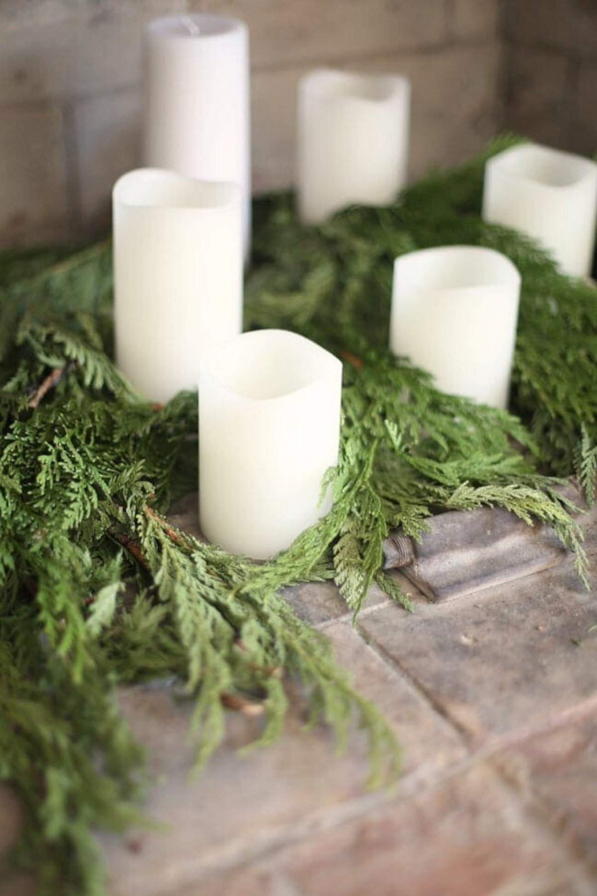 A mantle adorned with battery operated candles and greenery.