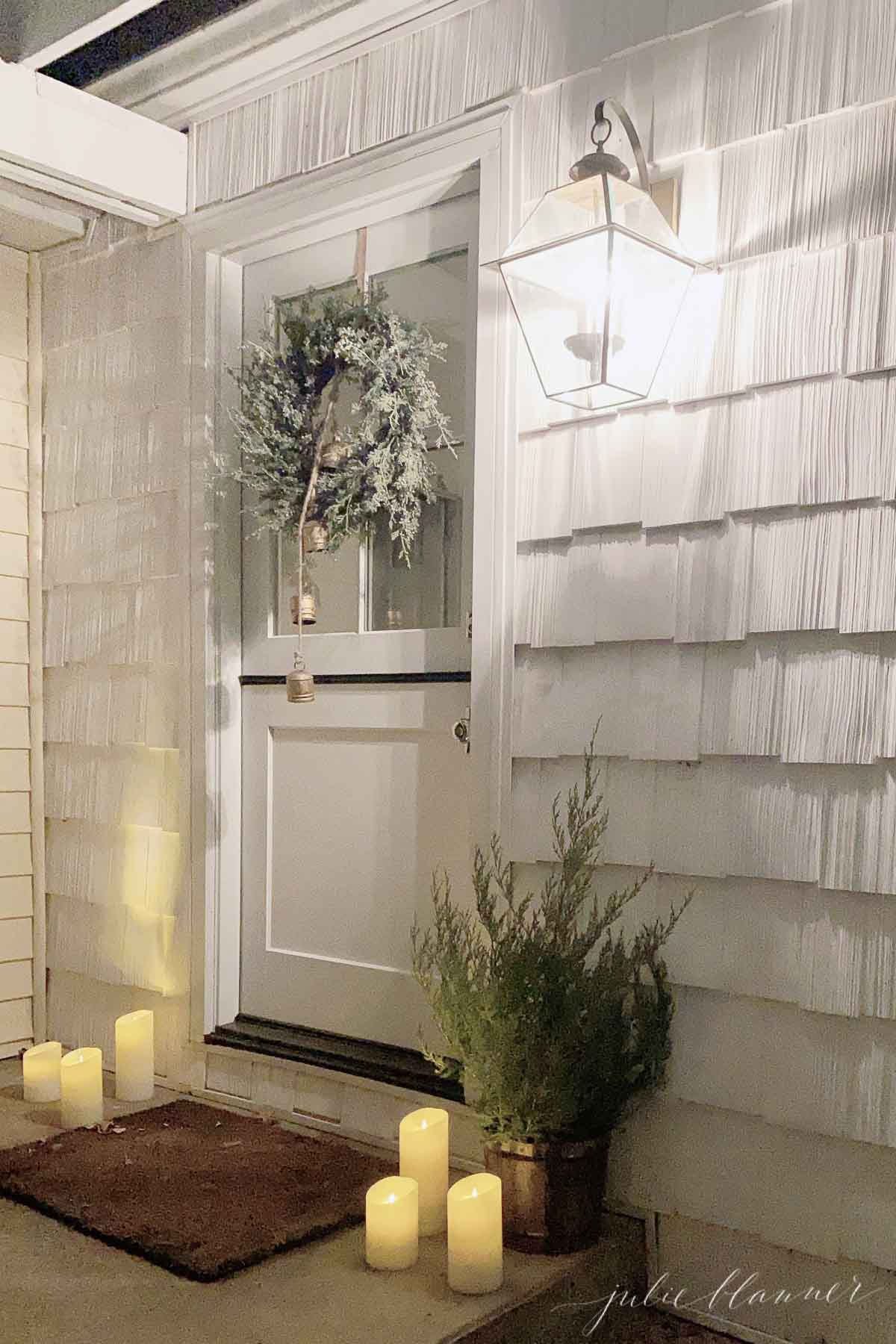 A front porch with LED candles and a wreath.