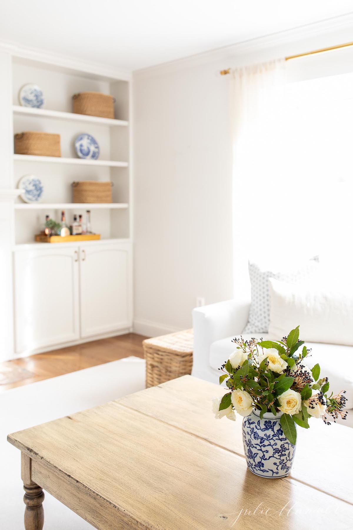 A living room with white furniture and a blue vase.