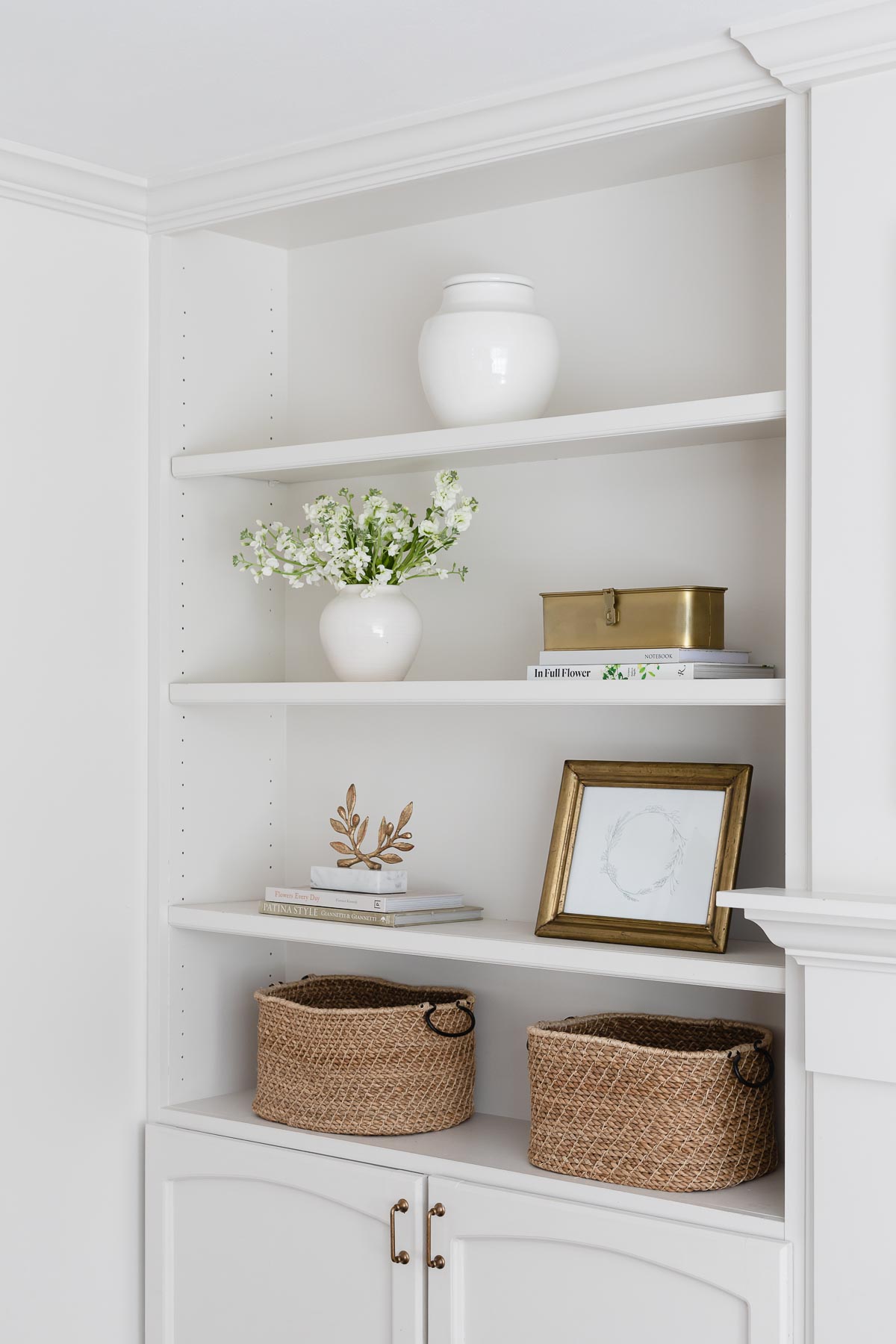 A living room with white shelves and baskets.