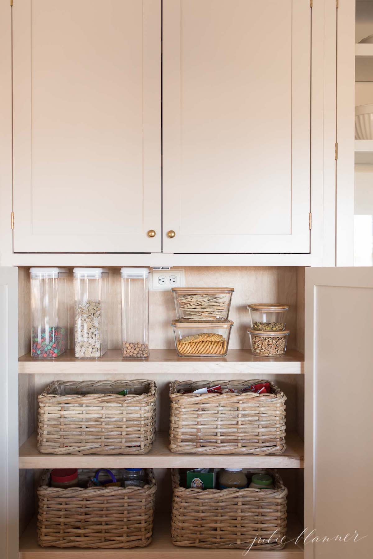 A white kitchen with wicker baskets for home organization in the cabinets.