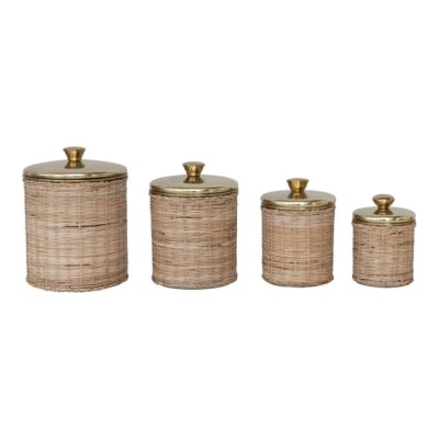 Four rattan canisters for kitchen counter organization, featuring brass lids.