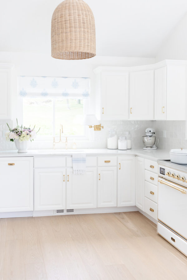 A white kitchen with wooden floors and a pendant light that offers efficient kitchen counter organization.