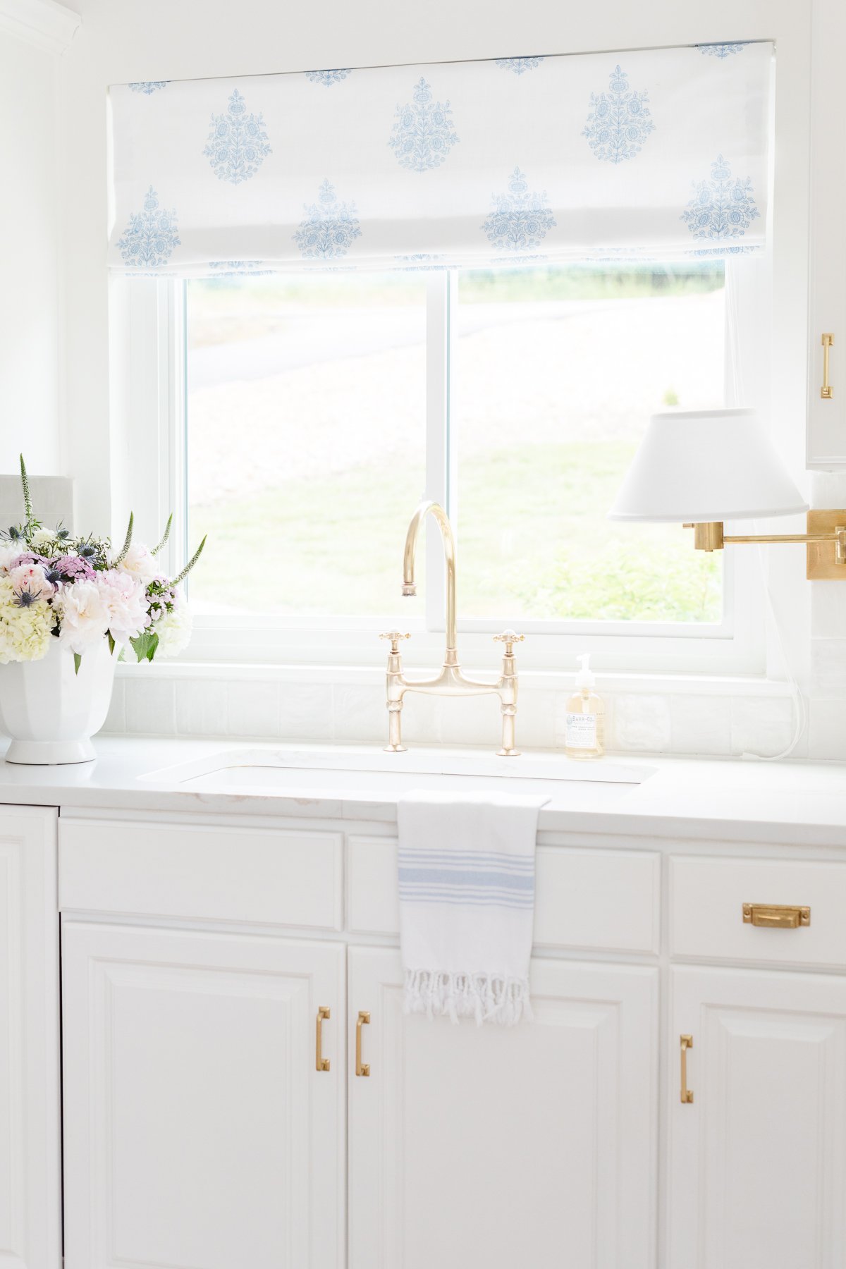 A white kitchen with gold hardware and kitchen counter organization.