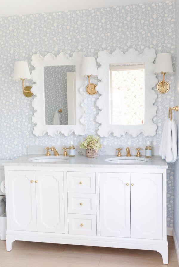 A white bathroom with blue and gold wallpaper.