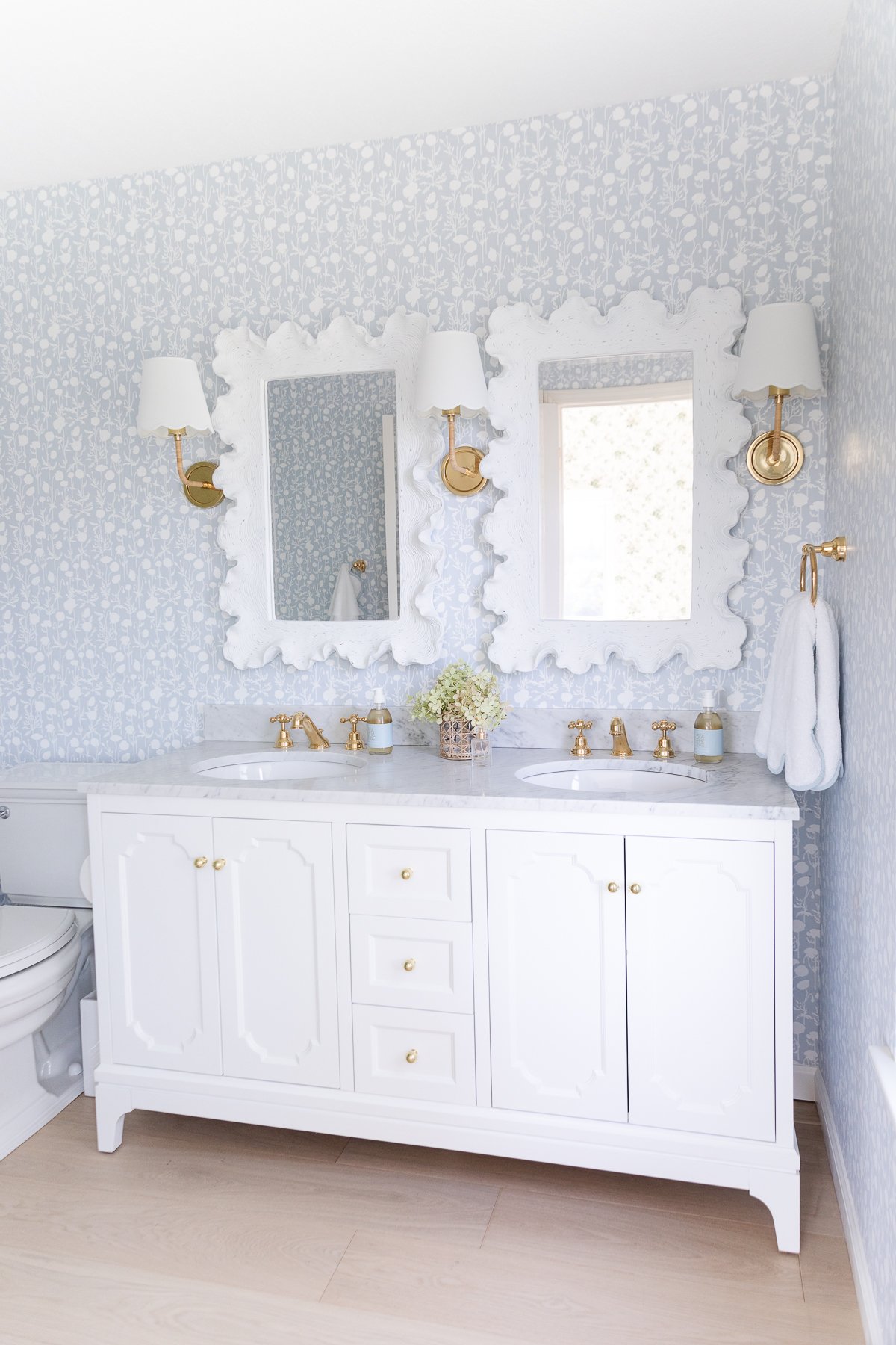 A white bathroom with blue wallpaper.