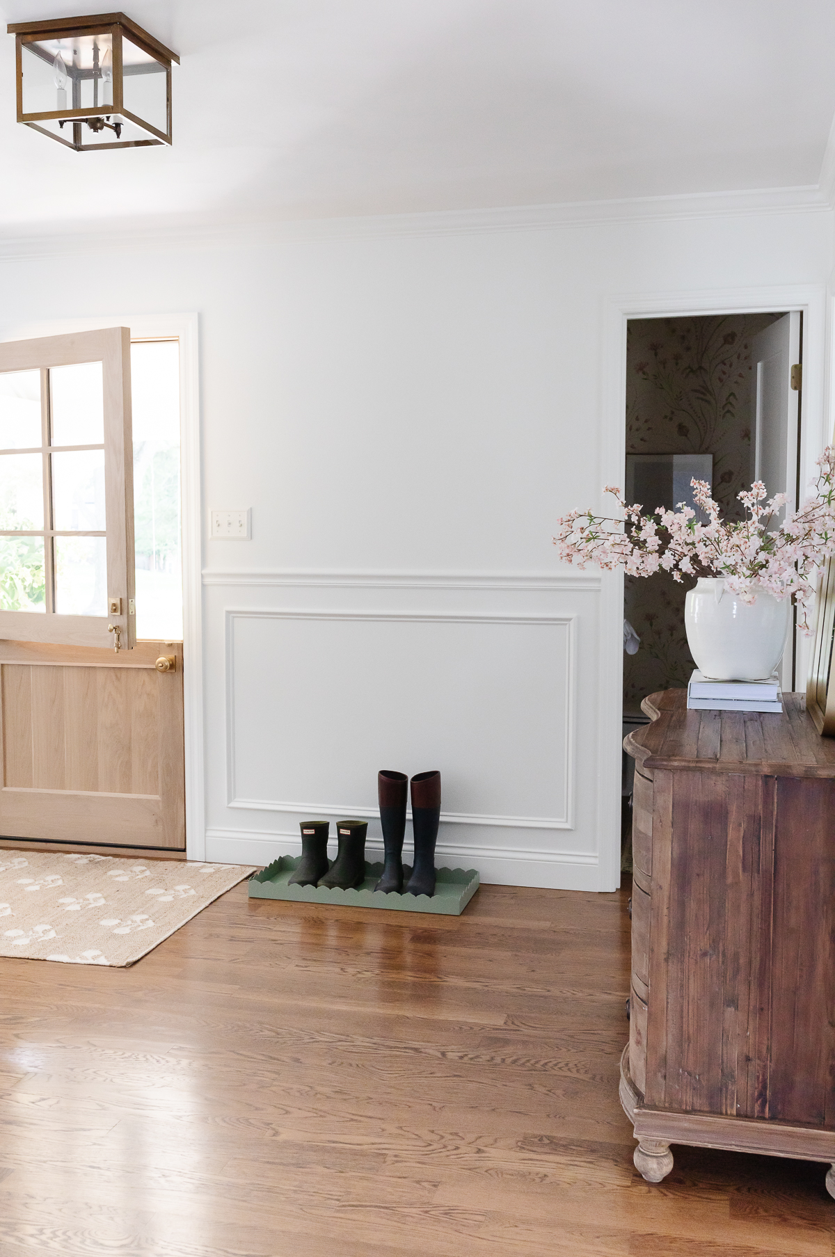 A living room with hardwood floors and a door featuring a curved dresser.