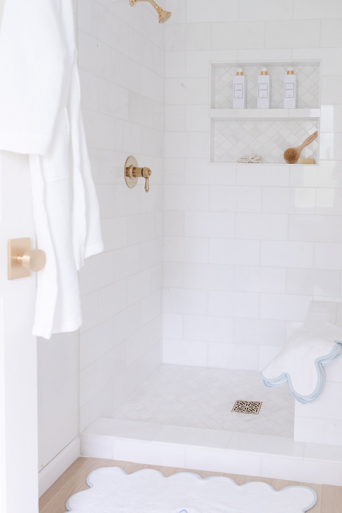 A white bathroom with a blue shower rug.