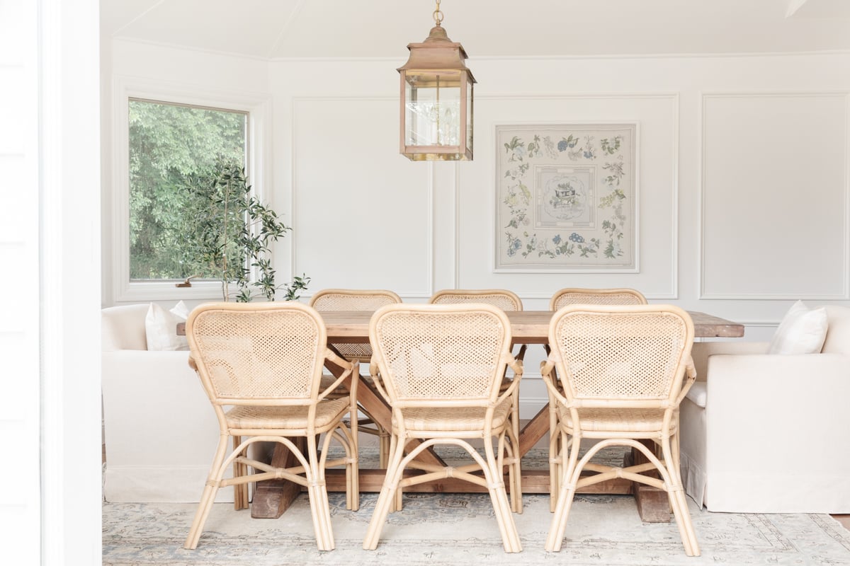 Before, a dining room with wicker chairs and a chandelier. After, the same dining room with wicker chairs and a chandelier.