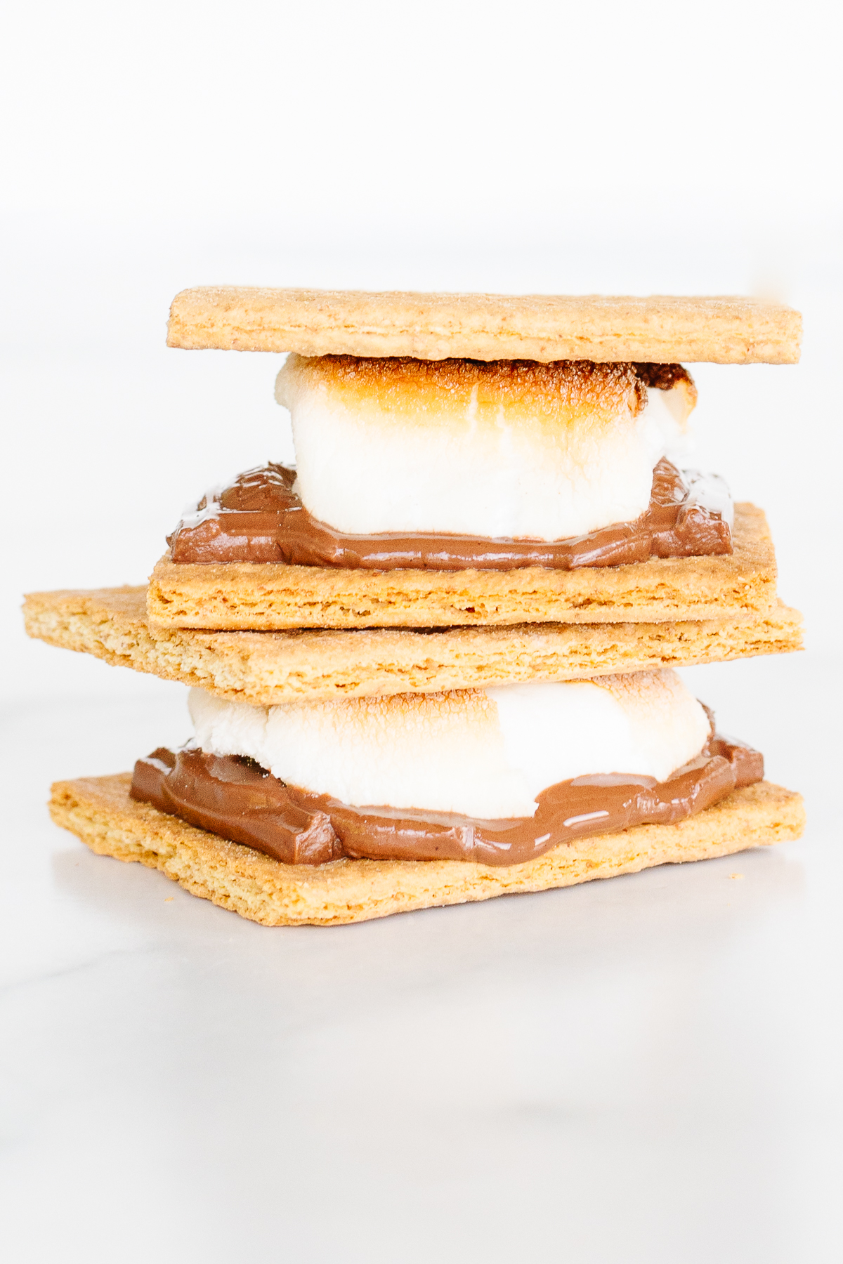 Three s'mores stacked on top of each other, toasted in the oven.