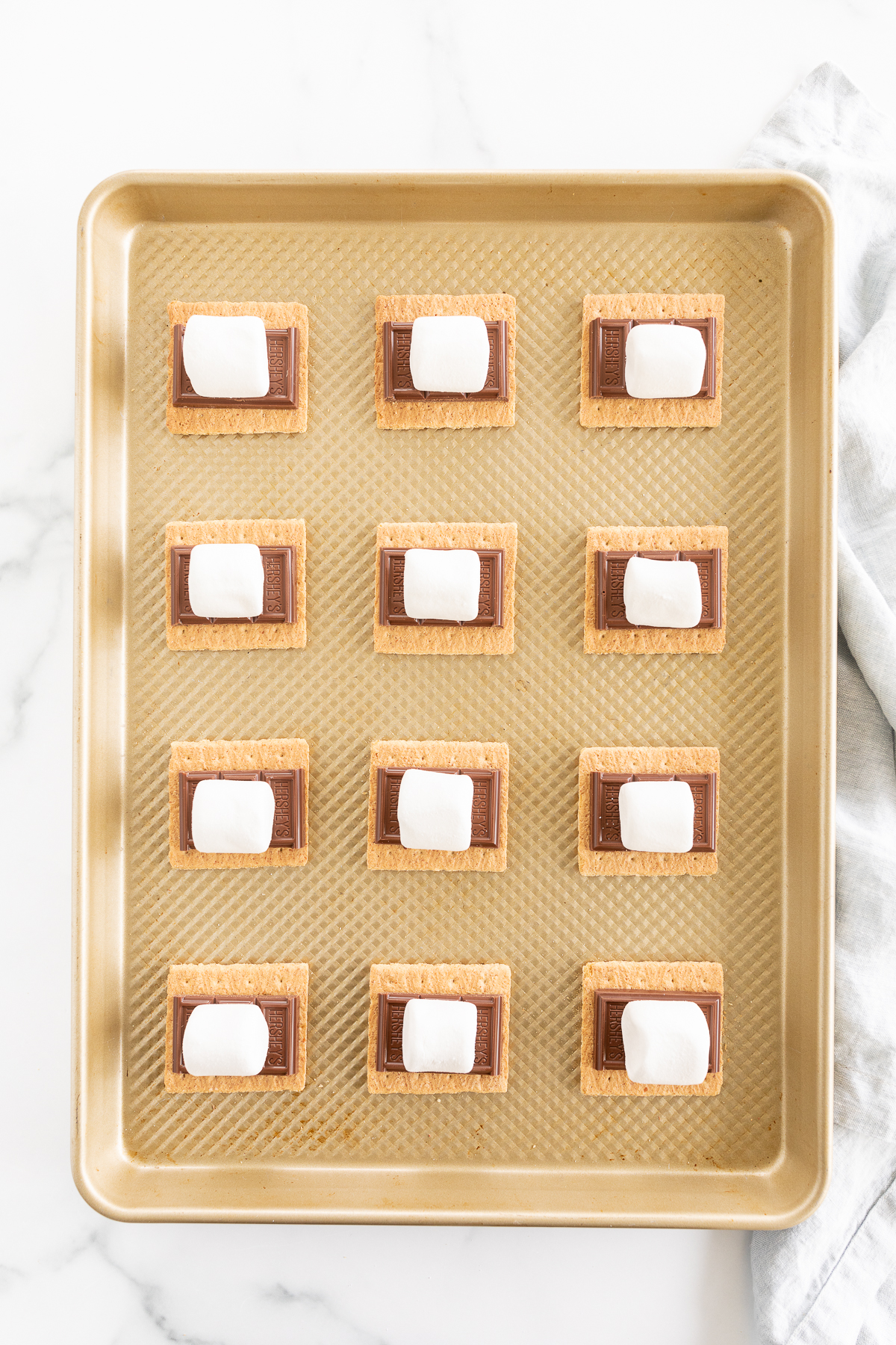 Oven-baked s'mores with marshmallow and graham crackers on a baking sheet.