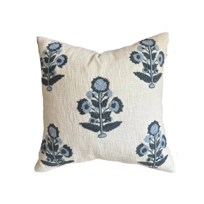 A square throw pillow featuring a pattern of blue flowers and green leaves on an off-white background gives you that stylish Pottery Barn look for less.