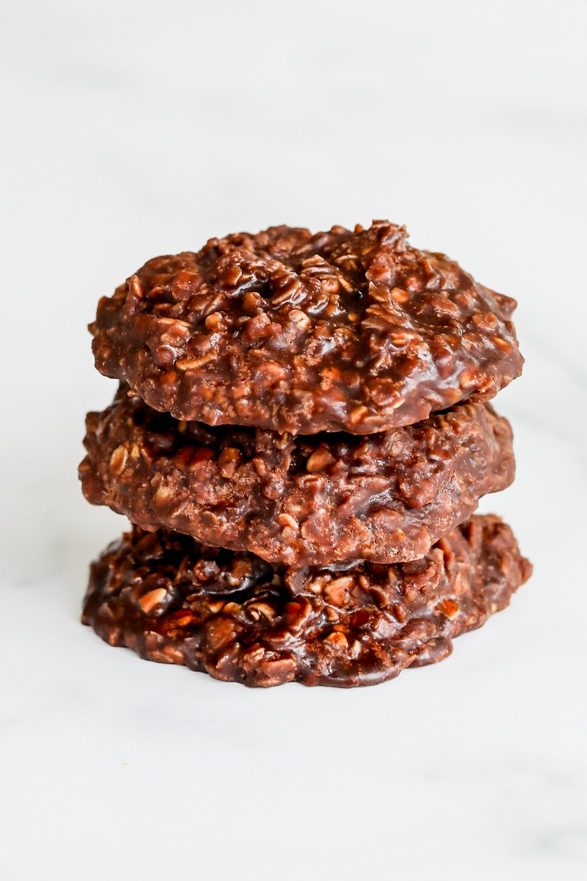A stack of chocolate no bake cookies, also known as preacher cookies, on a white surface.
