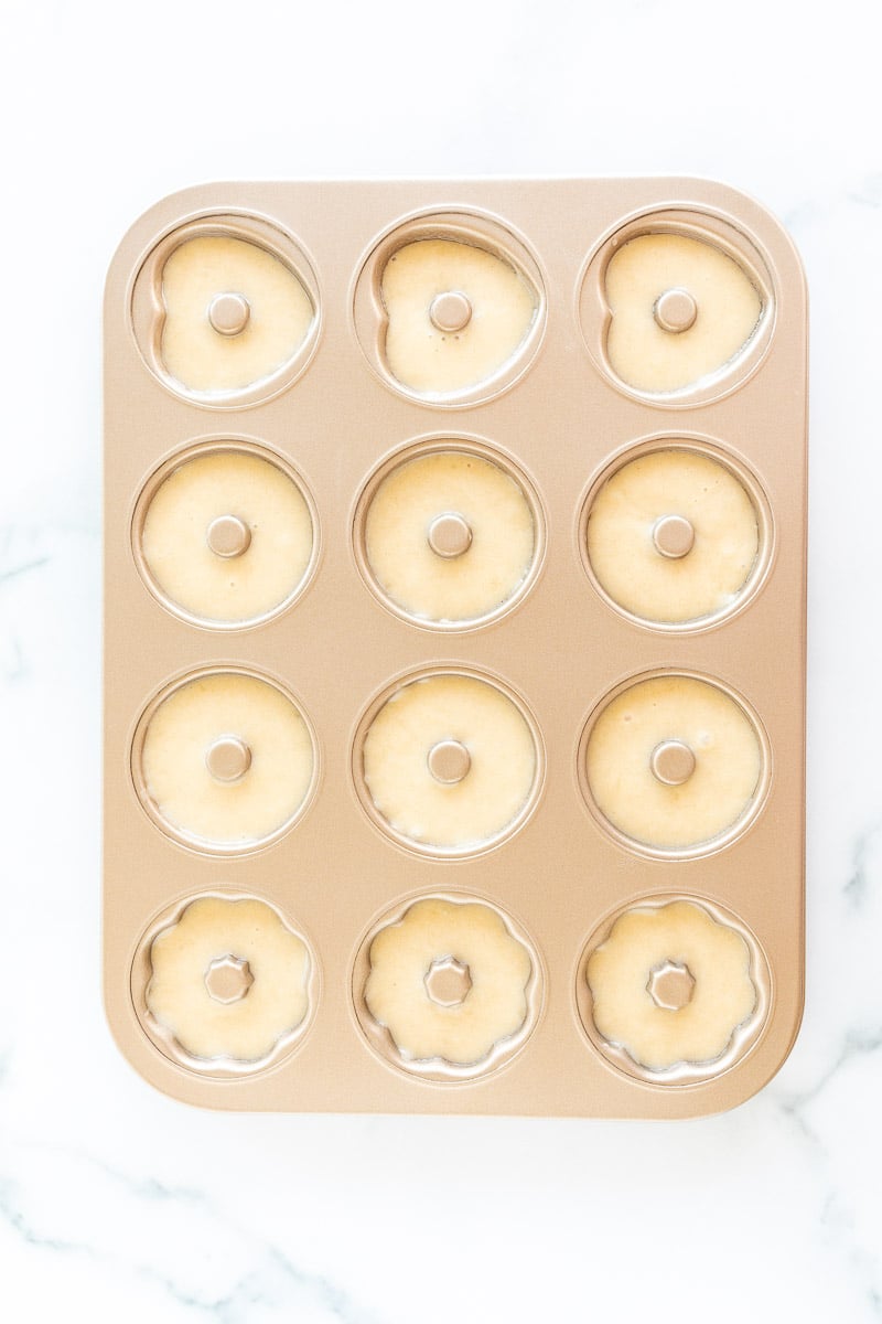 A muffin tin with a dozen valentine cupcakes in it.