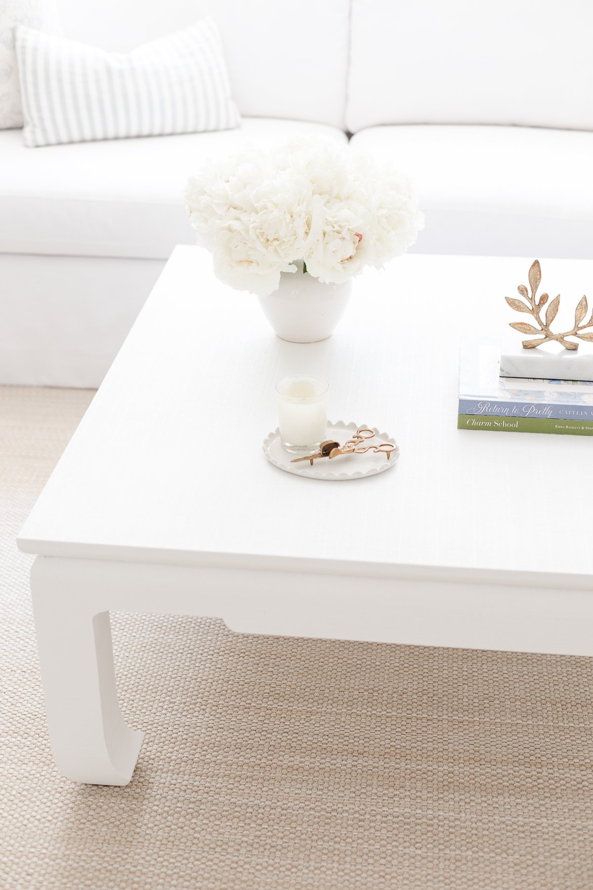 A white coffee table in a living room with an outdoor sisal rug.