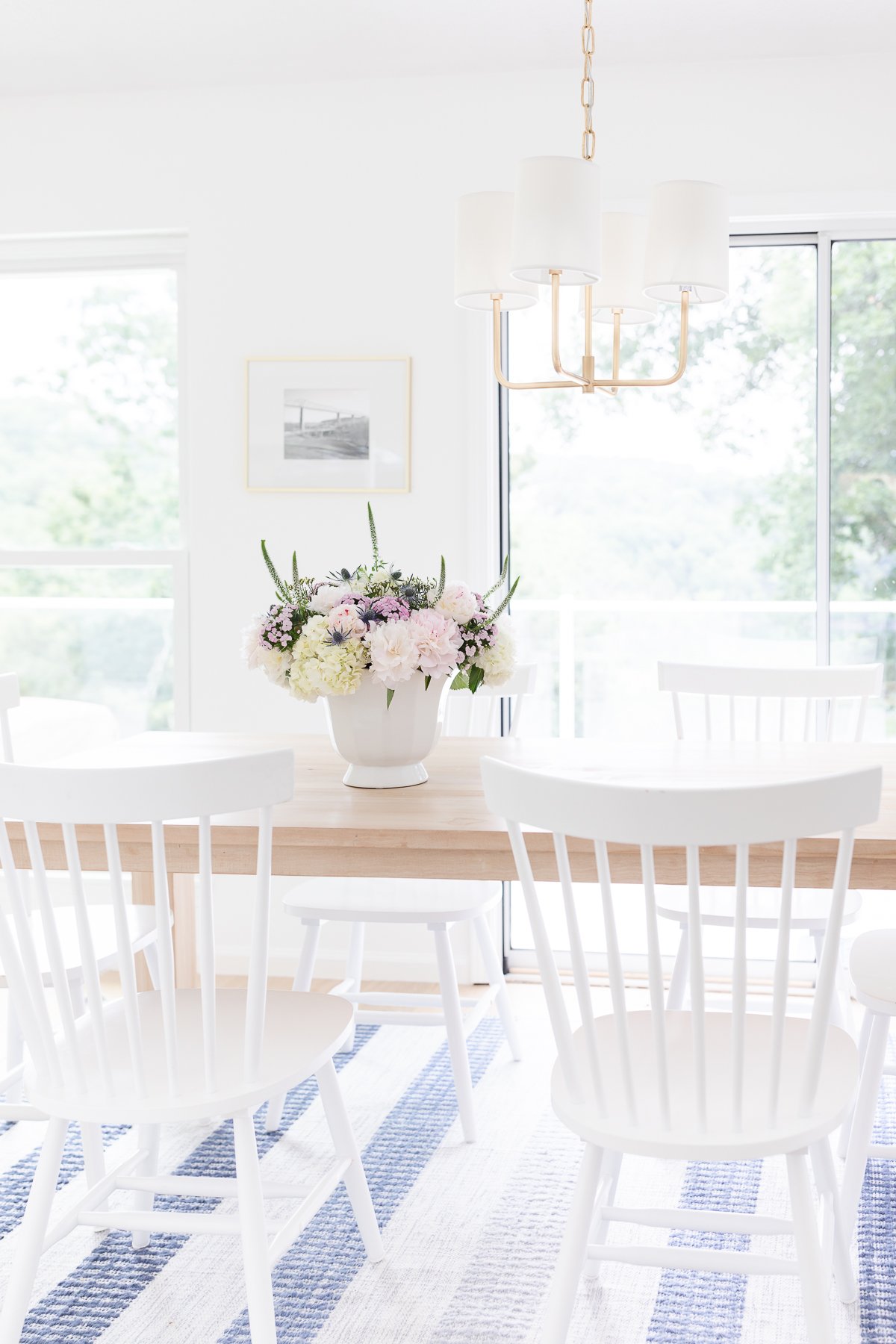 A white dining room with blue striped chairs, perfect for lake house decor.
