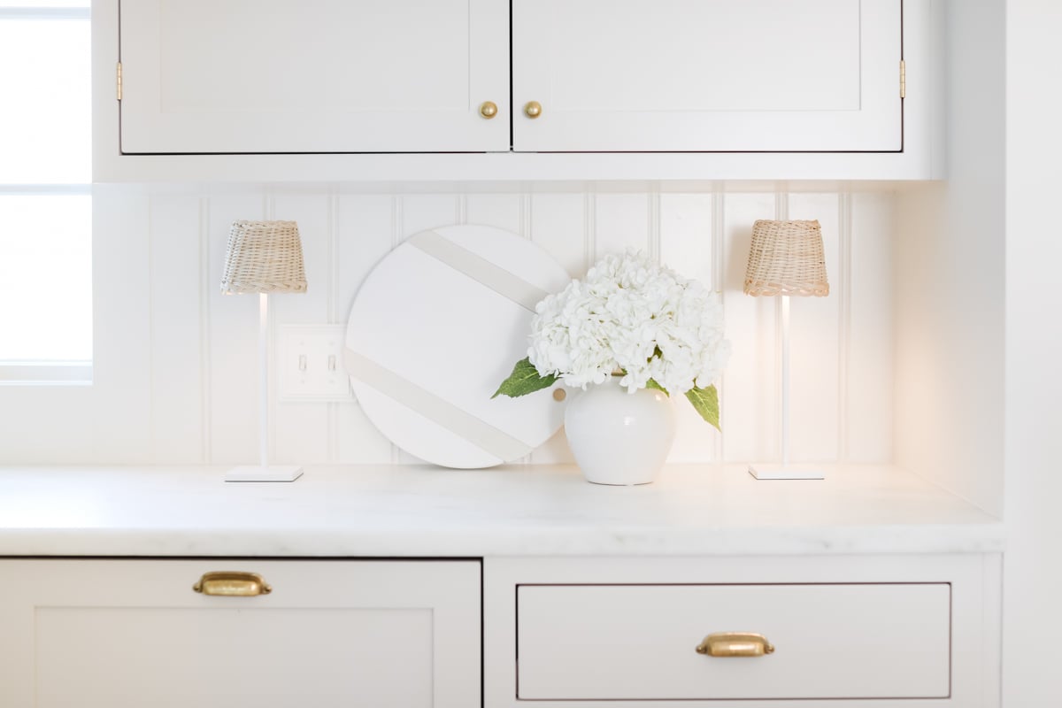 A white kitchen with white cabinets and a vase of flowers, enhanced with a few amazon gadgets.