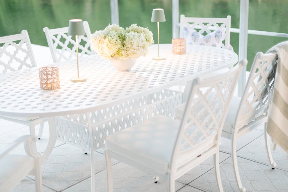 A white patio table and chairs with a gorgeous view of a lake.