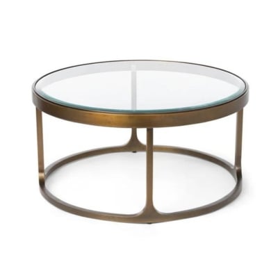 A round coffee table with a brass frame and glass top, offering an Arhaus look for less.