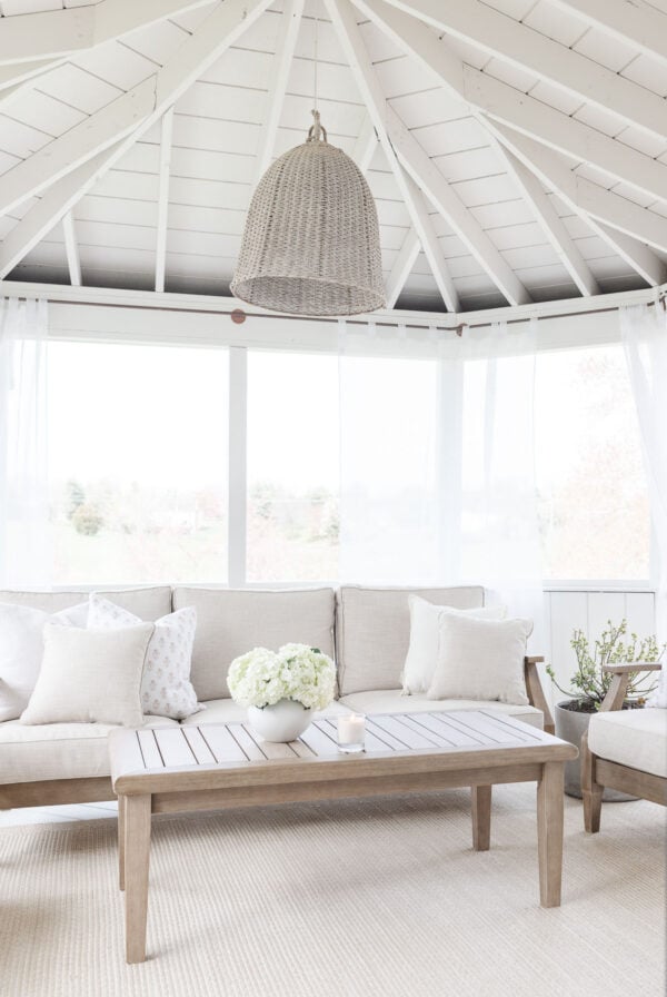 A white screened in porch with a basket pendant light.