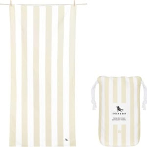 A beige and white striped towel sways on the line, accompanied by a matching drawstring bag adorned with a logo. Ideal as Easter basket fillers, these stylish essentials bring charm and functionality to your festive gift-giving.