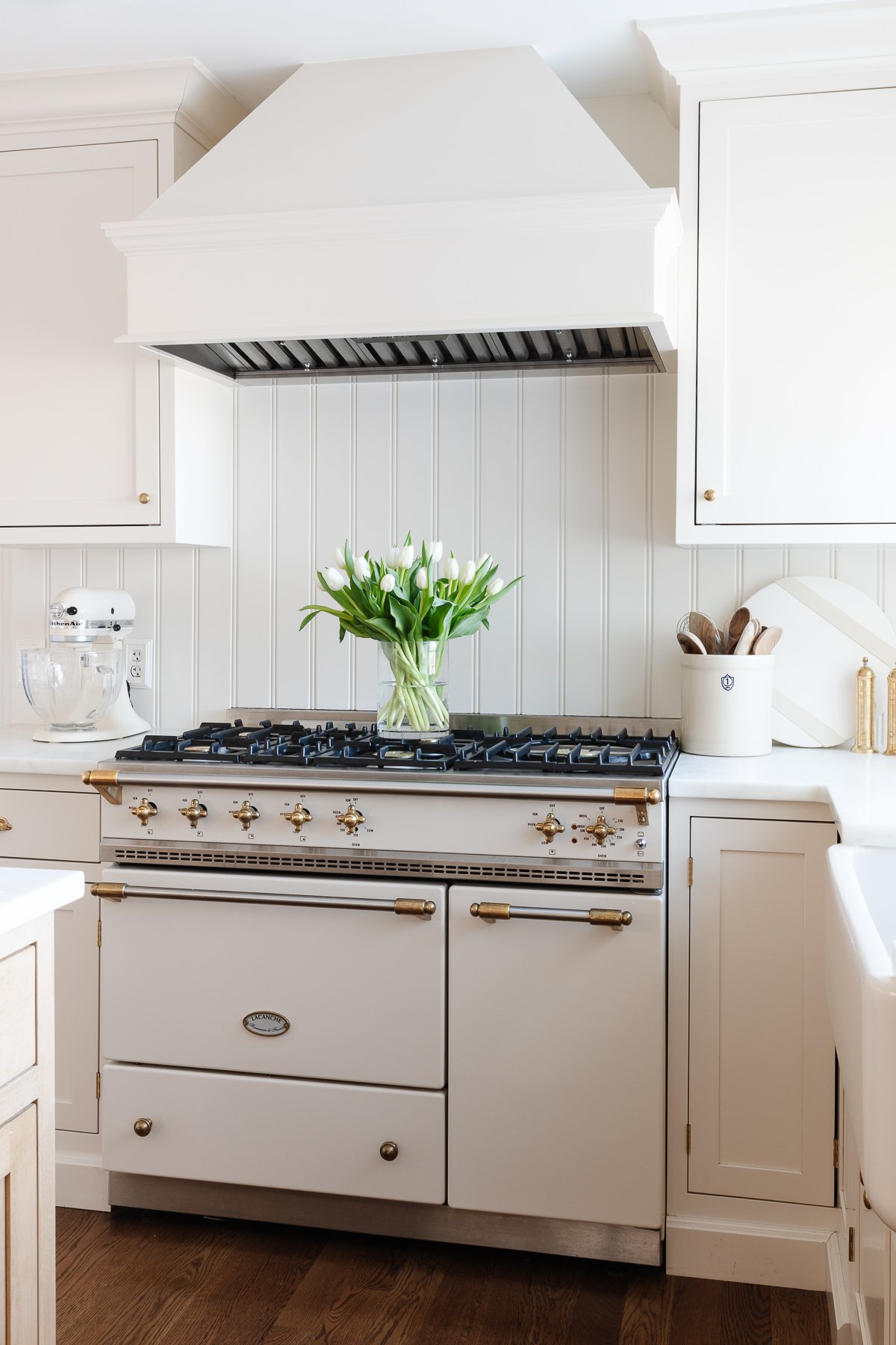A white kitchen with a gold La Canche hood.