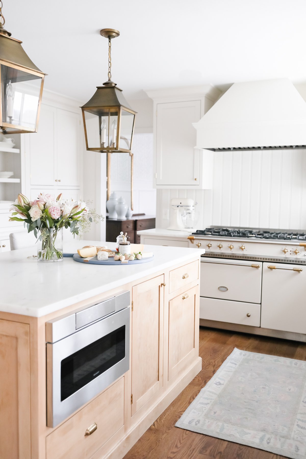 A white kitchen with a lacanche oven and a white island.