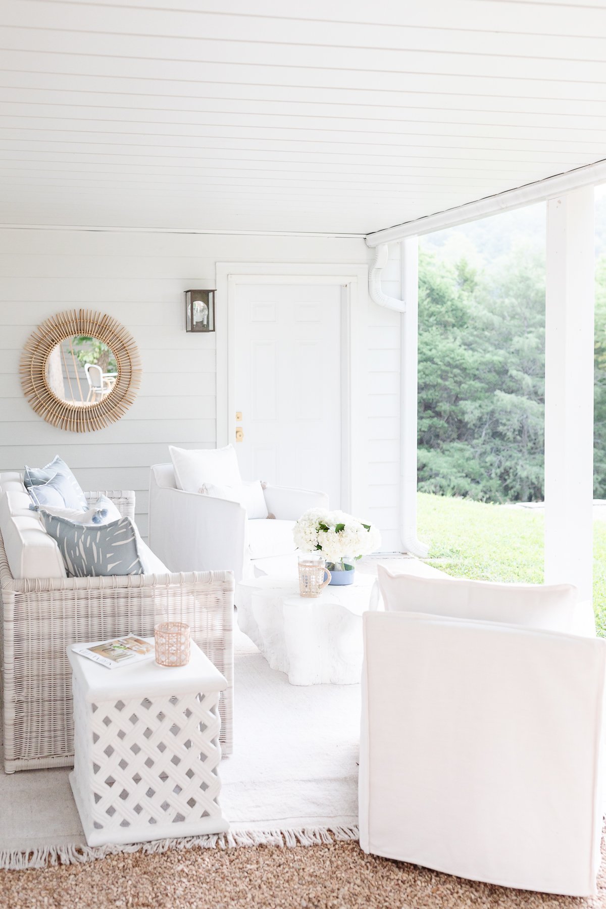 A white porch with Serena and Lily outdoor furniture and a mirror.