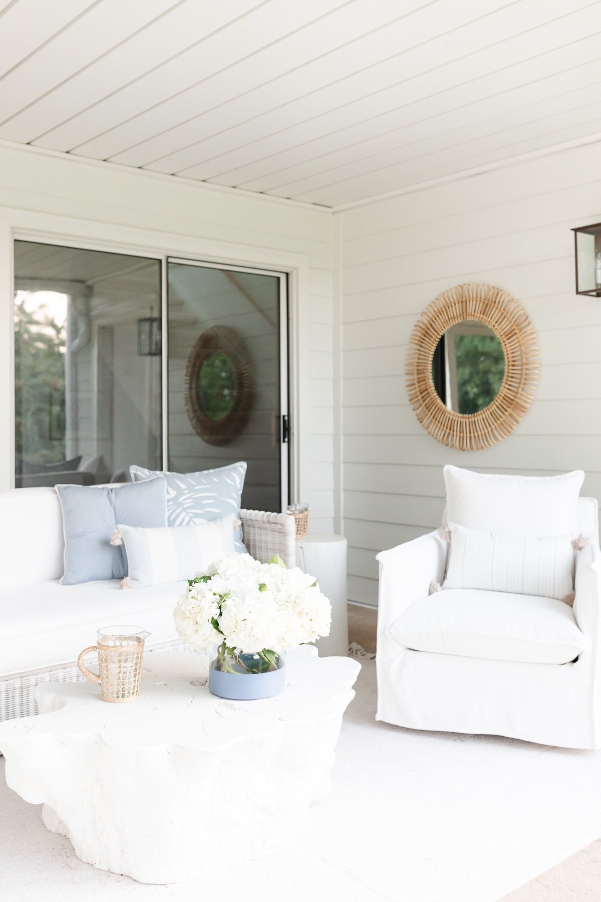 A white living room with white Serena and Lily outdoor furniture and a mirror.