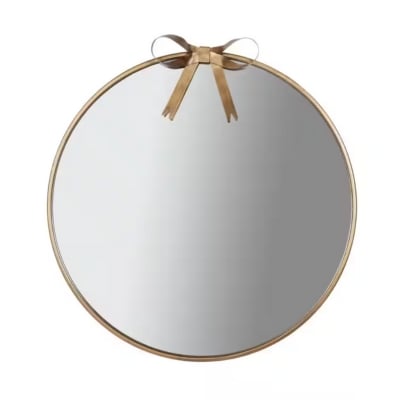 A round mirror with a bow on it.
