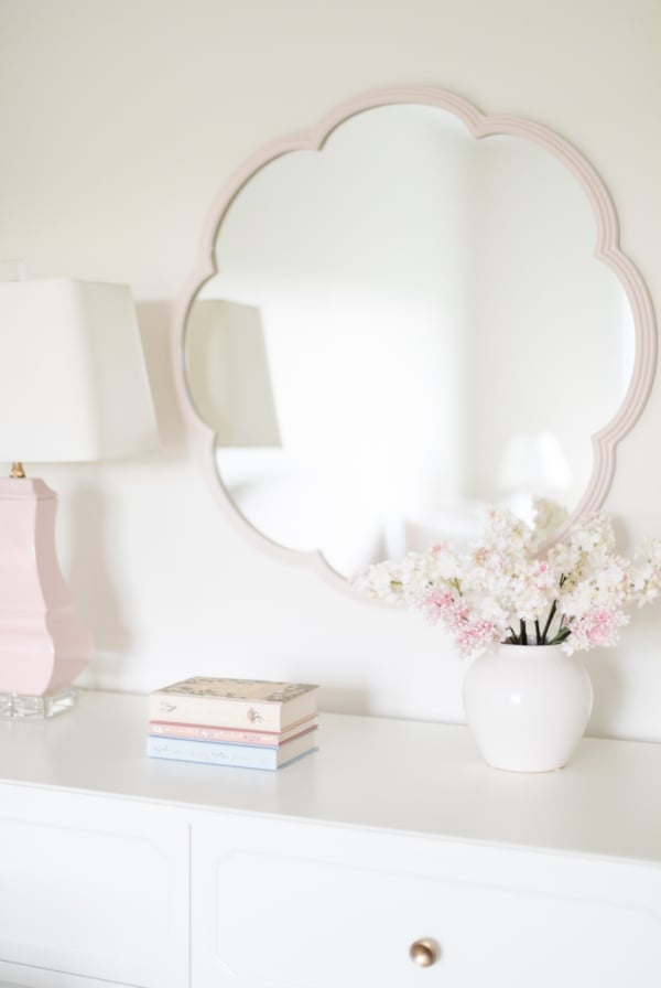 A white dresser with a pink mirror.