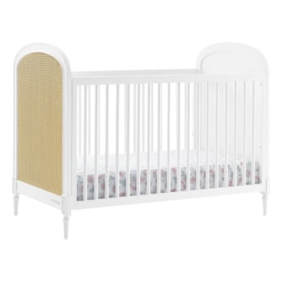 A white crib with a wicker headboard and footboard.