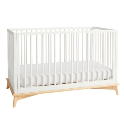 A white crib with wooden legs.
