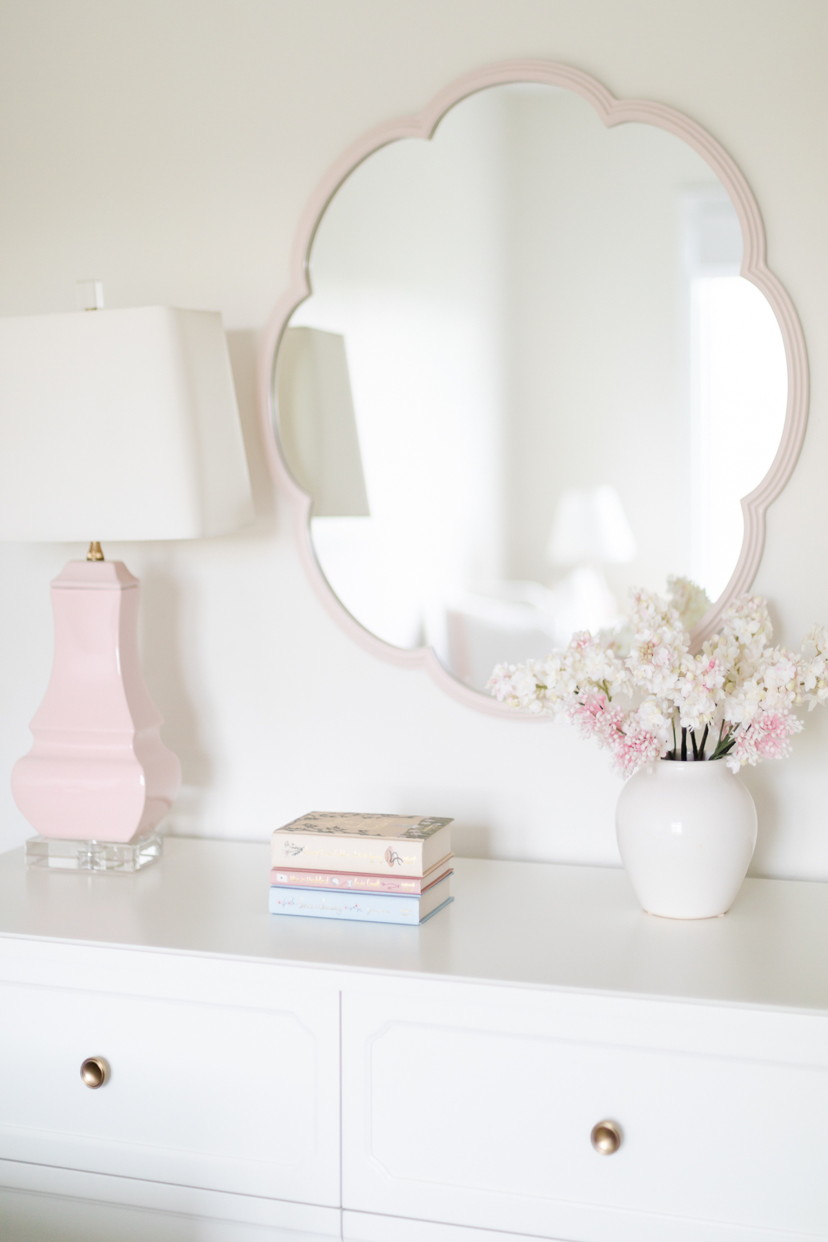 A white dresser with pink flowers and a mirror.