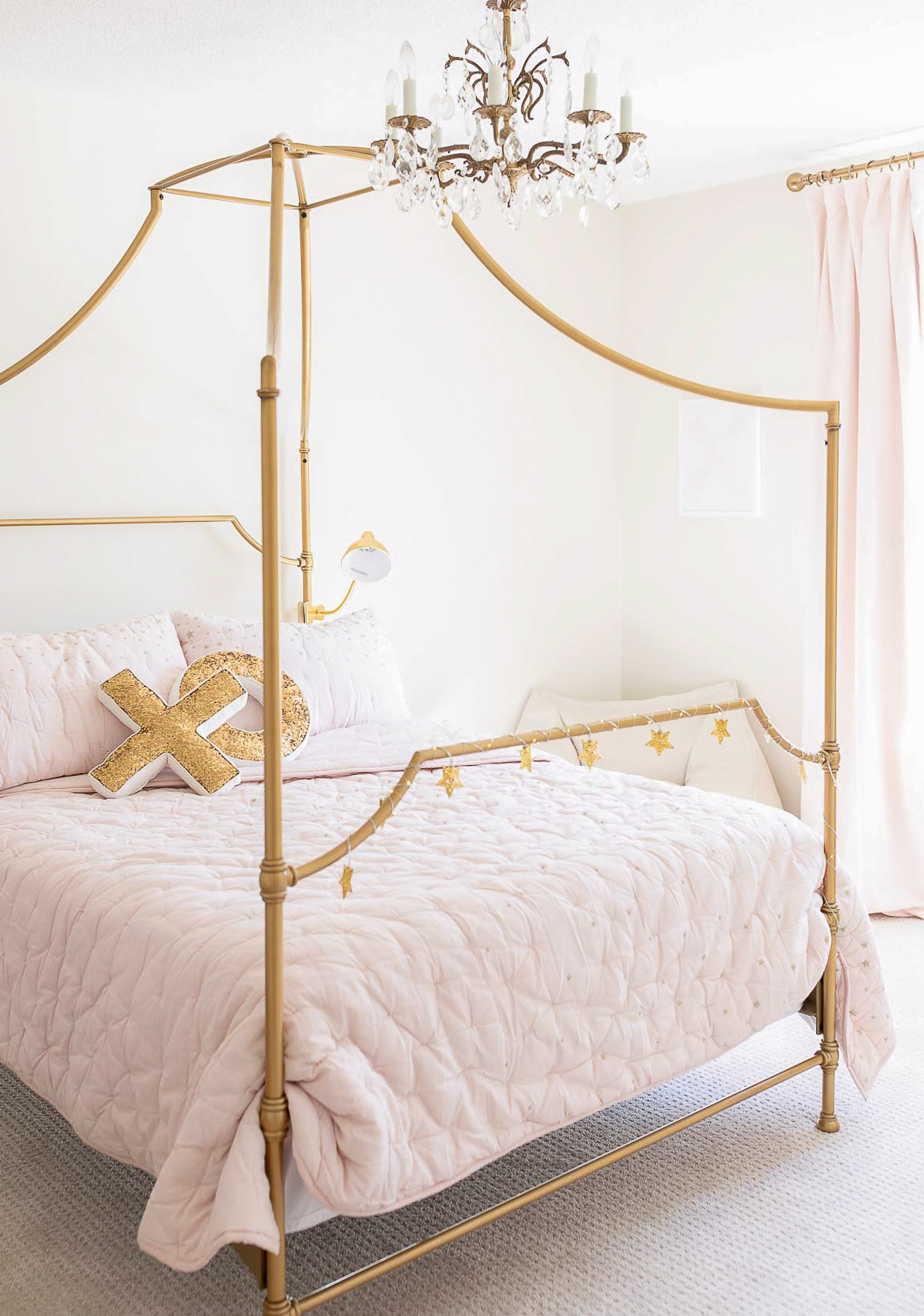 A bedroom with a gold canopy bed and pink bedding.