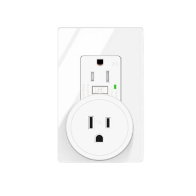 A white smart plug, one of the latest Amazon gadgets, is inserted into a standard wall outlet, with a green indicator light visible on the outlet.