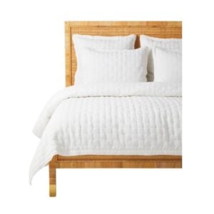 A Serena and Lily-inspired white bed with a wooden headboard.