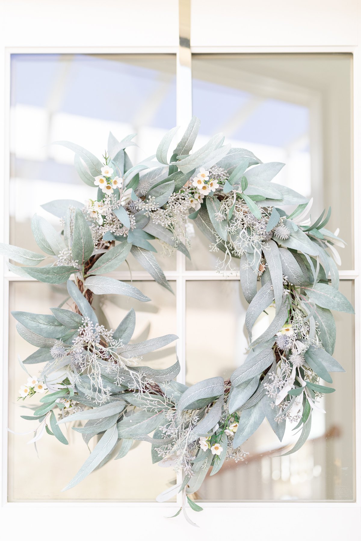 A eucalyptus wreath hangs on a window, perfect for spring.