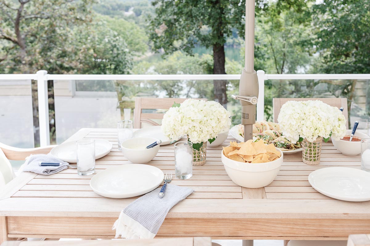 A patio furniture set with white plates, bowls and utensils.