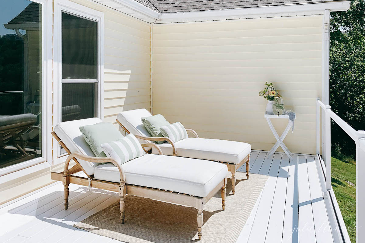 Two white patio furniture lounge chairs on a white porch.